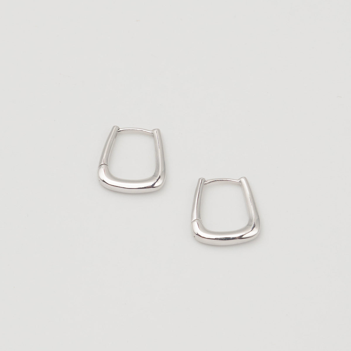 Rhodium-plated sterling silver geometric hoop earrings with a polished finish on a light background