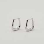 Rhodium-plated sterling silver geometric hoop earrings with a polished finish on a light background