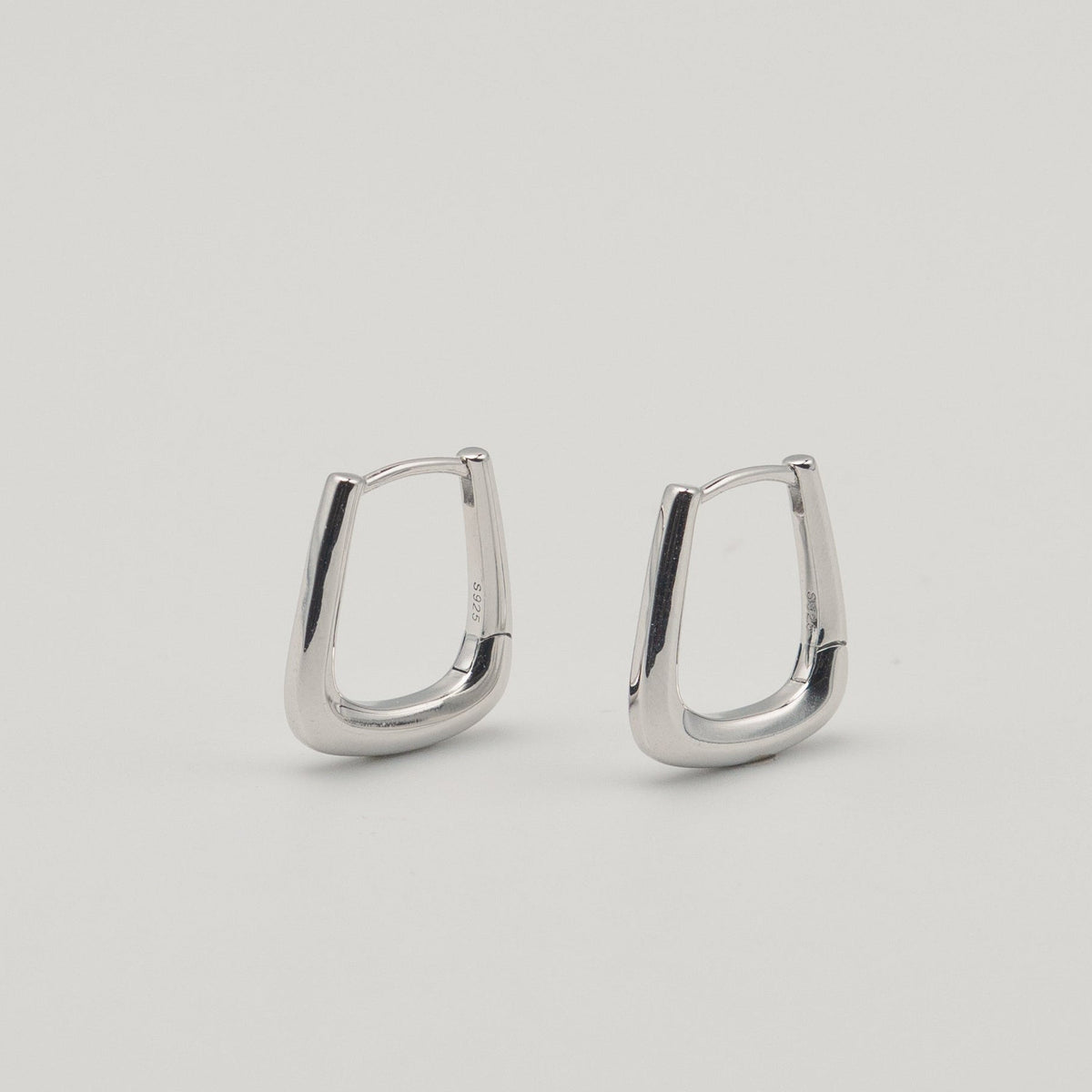 Rhodium-plated sterling silver geometric hoop earrings with a polished finish on a light background