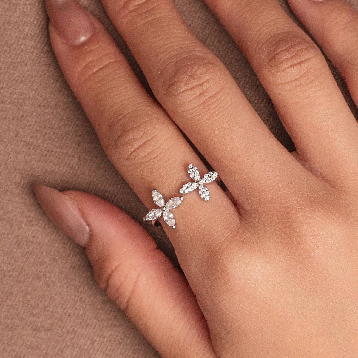 Rhodium-plated sterling silver open ring with marquise-cut clear stones arranged in floral motifs, worn on the finger
