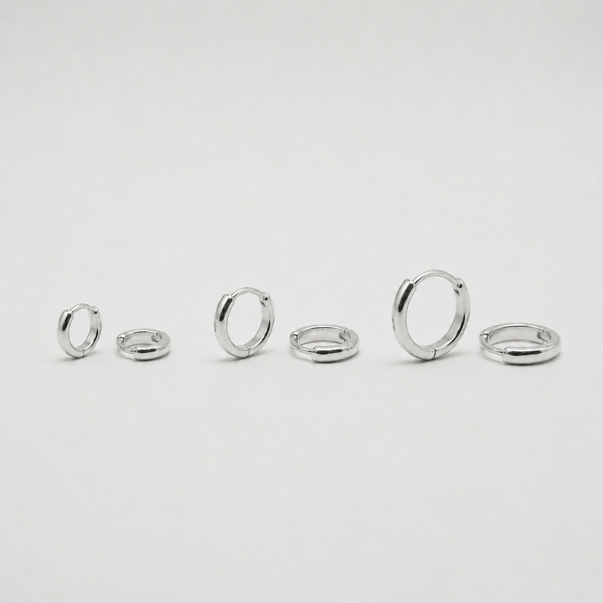 Rhodium-plated sterling silver minimalist huggie earrings with a smooth polished finish