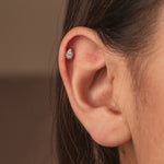 Rhodium-plated sterling silver teardrop round-back stud earring with clear cubic zirconia stones worn on helix