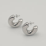 Polished silver stainless steel chunky hoop earrings on a light background