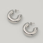 Polished silver stainless steel chunky hoop earrings on a light background