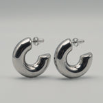 Polished silver stainless steel chunky hoop earrings on a light background