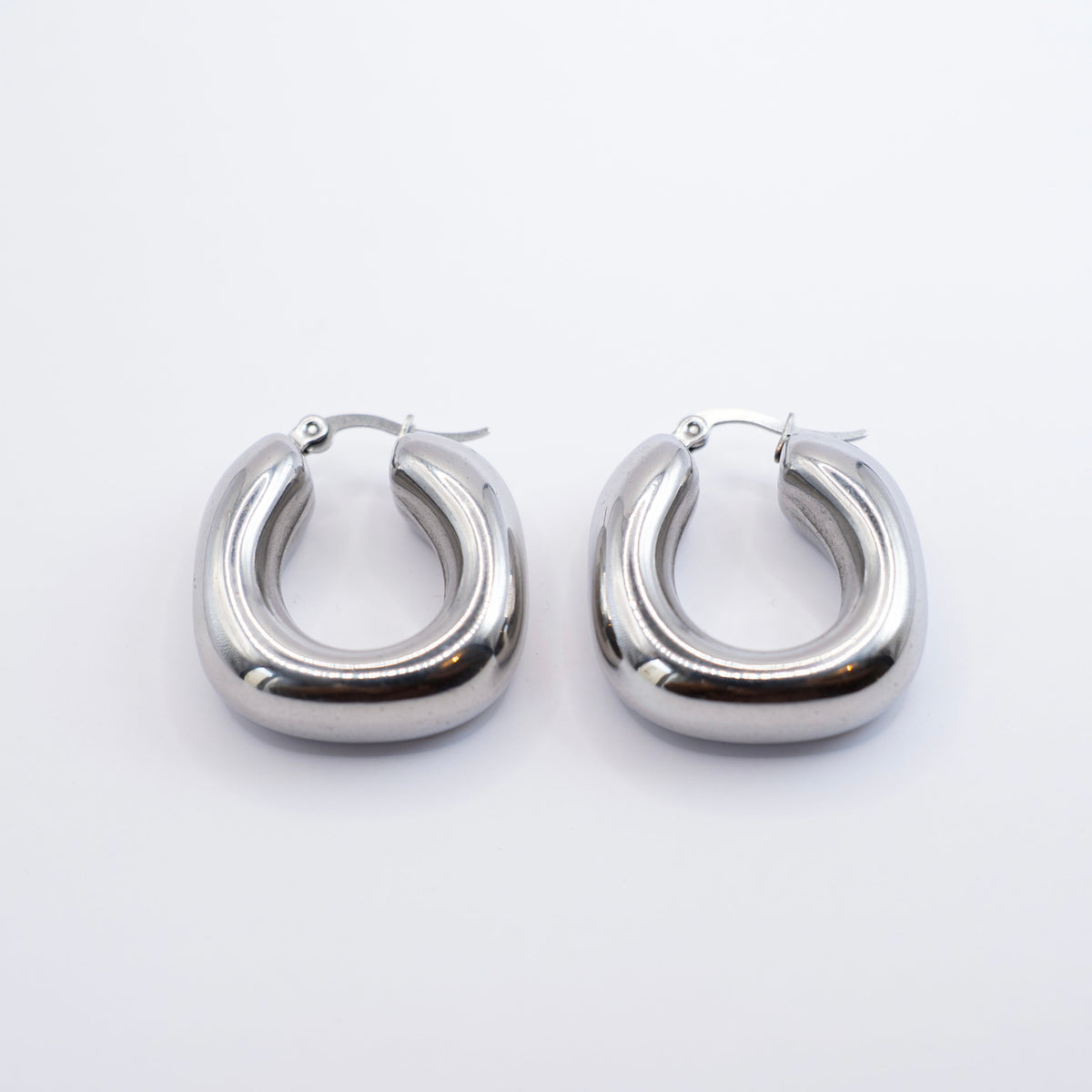 Polished silver stainless steel chunky rounded hoop earrings on a white background