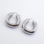 olished silver stainless steel chunky rounded hoop earrings on a white background