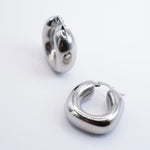Polished silver stainless steel chunky rounded hoop earrings on a white background