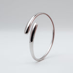 Polished silver stainless steel open cuff bangle bracelet on a light background