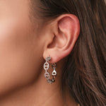 Silver stainless steel hoop earrings with pavé cubic zirconia oval link details worn on the ear
