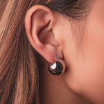 Silver stainless steel sphere drop earrings with a polished finish worn on the ear