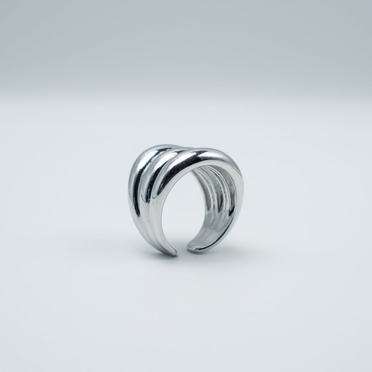 Polished silver stainless steel open ring with a chunky triple-band design on a light background