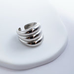 Polished silver stainless steel open ring with a chunky triple-band design on a light background