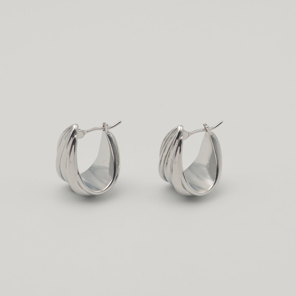 Polished silver stainless steel triple hoop earrings with a sculptural layered design