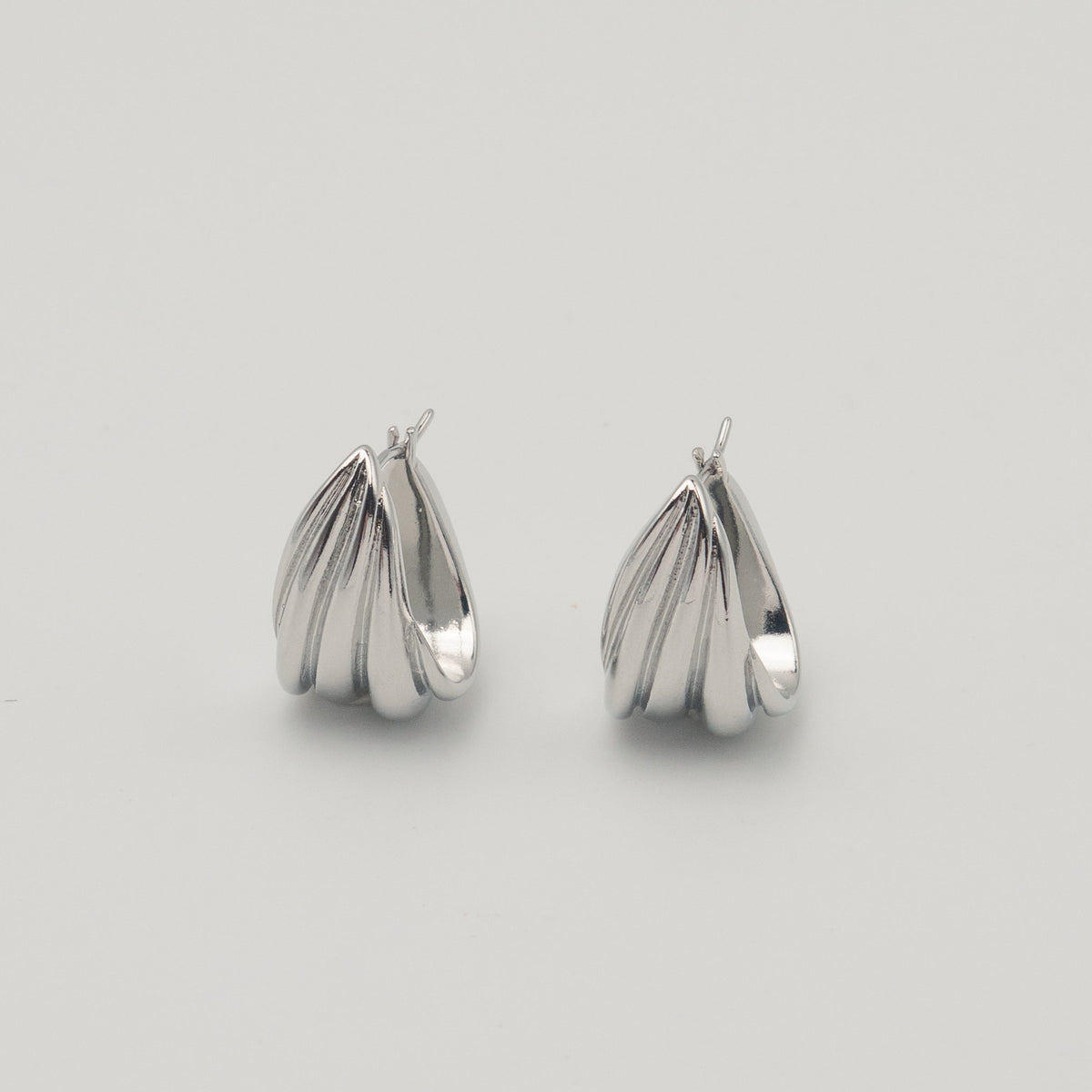 Polished silver stainless steel triple hoop earrings with a sculptural layered design