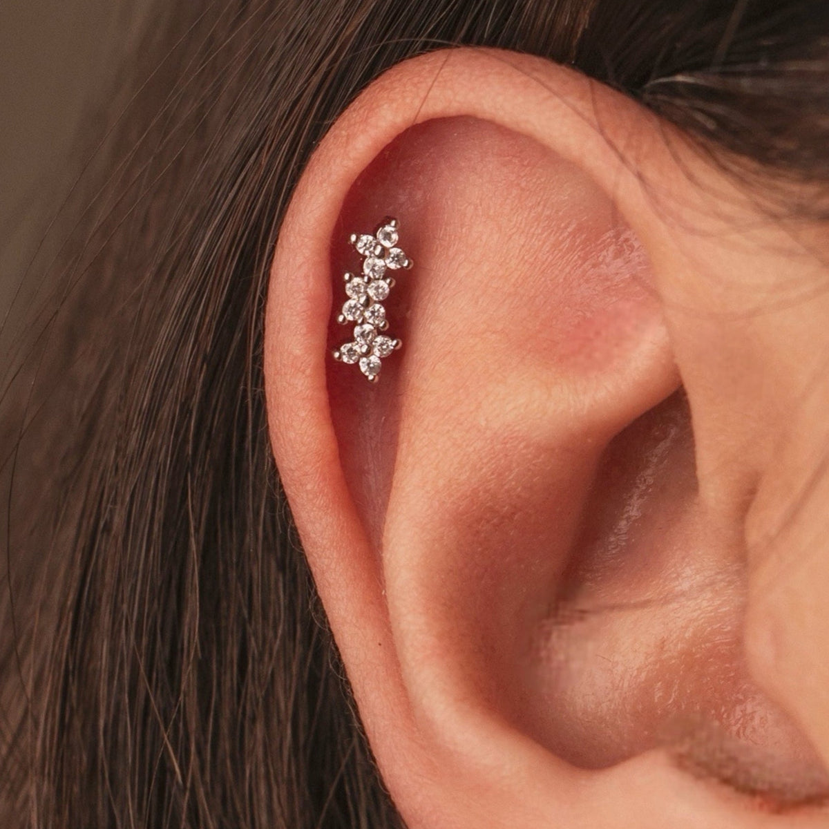 Stainless steel helix piercing earring with cubic zirconia stones worn on the ear