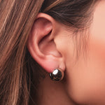 Polished sterling silver chunky clip earrings with a rounded dome shape on a light background worn on the ear