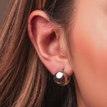 Polished sterling silver chunky clip earrings with a rounded dome shape on a light background worn on the ear