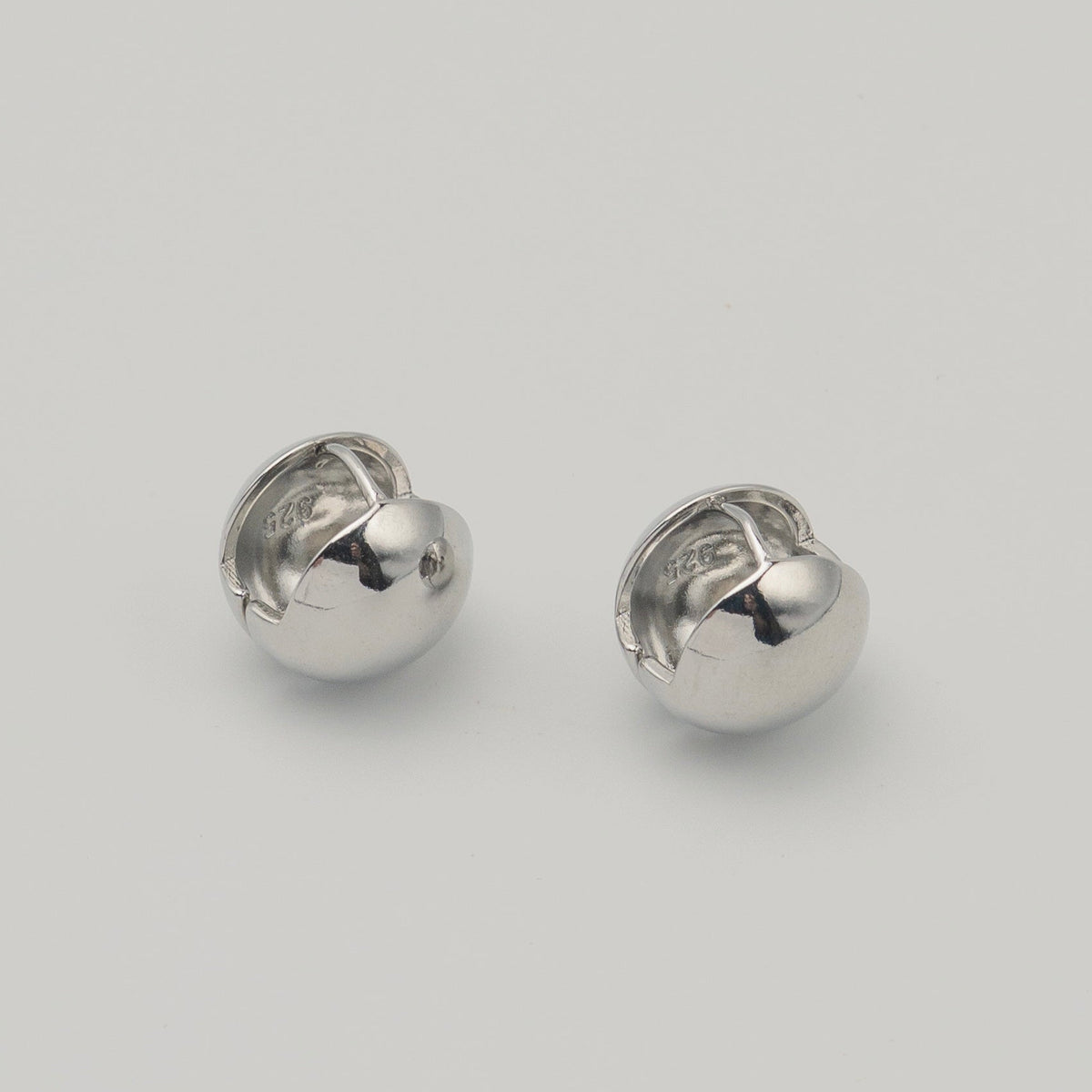 Polished sterling silver chunky clip earrings with a rounded dome shape on a light background