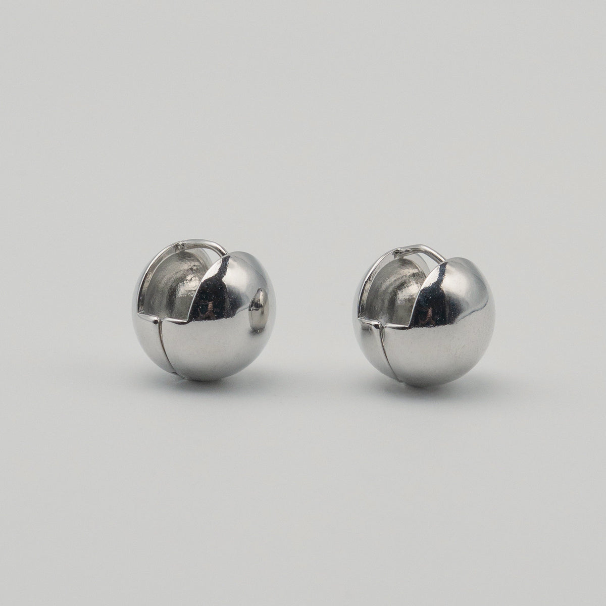 Polished sterling silver chunky clip earrings with a rounded dome shape on a light background