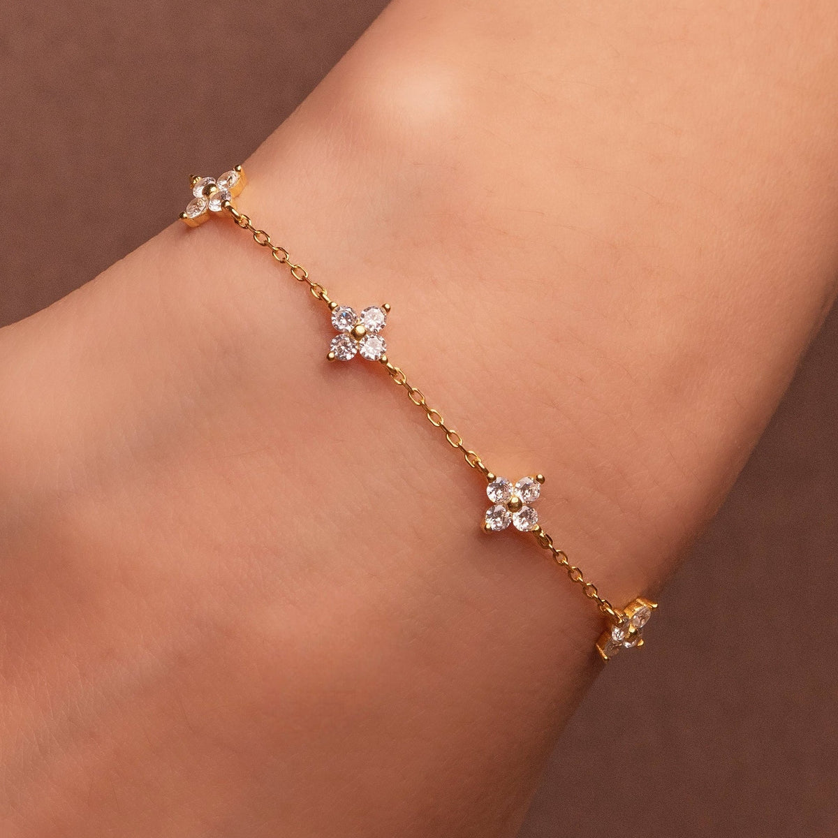 Gold-plated sterling silver flower bracelet with clear cubic zirconia stones.