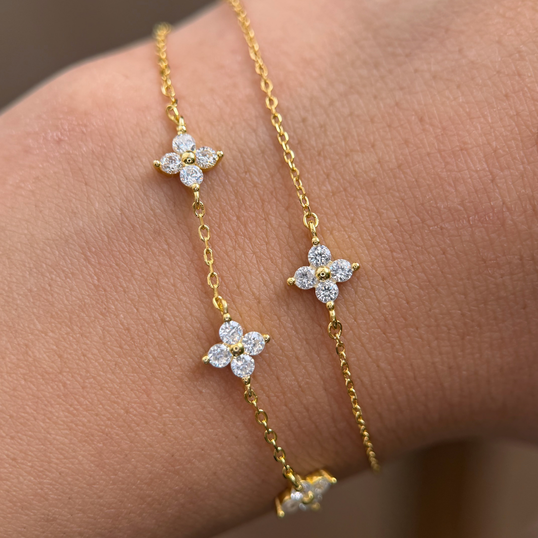 Gold-plated sterling silver flower bracelet with clear cubic zirconia stones.